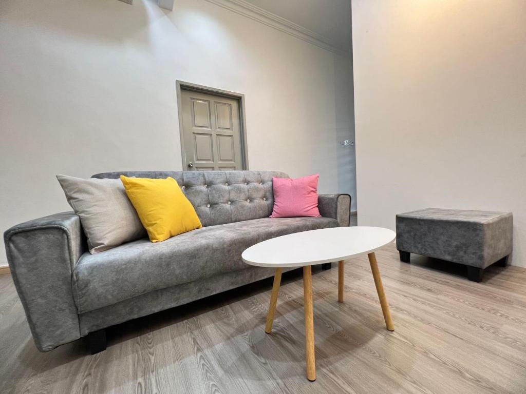 sala de estar con sofá gris y almohadas coloridas en Ngio Batu Pahat Homestay, en Batu Pahat