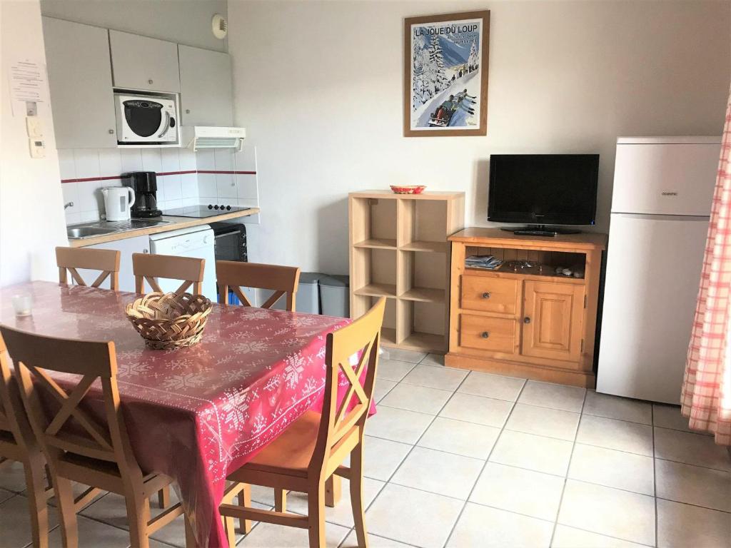 une cuisine avec une table avec des chaises et un réfrigérateur dans l'établissement Chalet Duplex 3 Pièces à La Joue du Loup - 7 Pers, Parking Gratuit, Animaux Acceptés - FR-1-504-97, à Saint-Étienne-en-Dévoluy