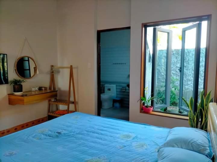 ein Schlafzimmer mit einem blauen Bett und einem großen Fenster in der Unterkunft Ly's homestay in Gia Nghĩa