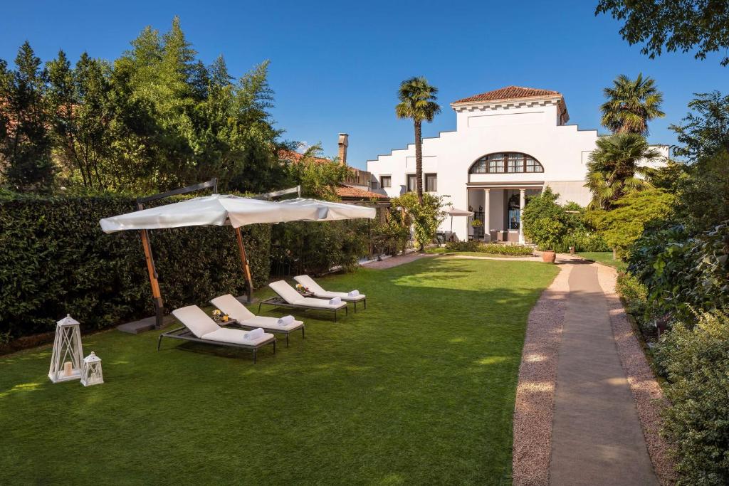 a lawn with lounge chairs and an umbrella in front of a house at NH Collection Grand Hotel Palazzo Dei Dogi in Venice