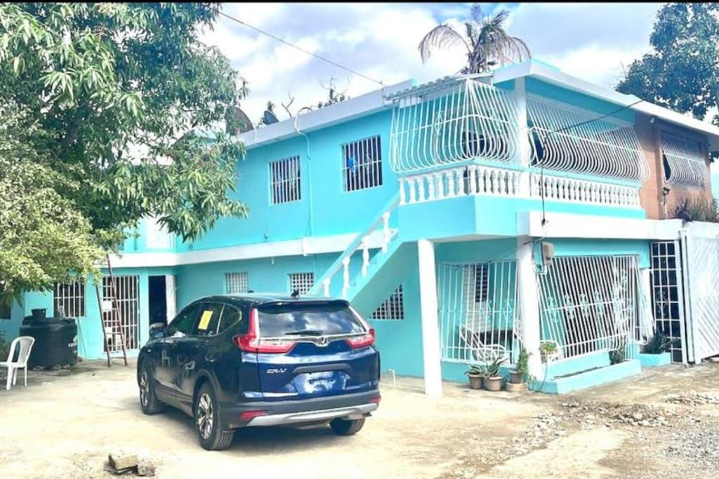 una casa azul con un coche aparcado delante de ella en agradable espanciosa casa de 3 habitaciones 3 bano, en La Ciénaga