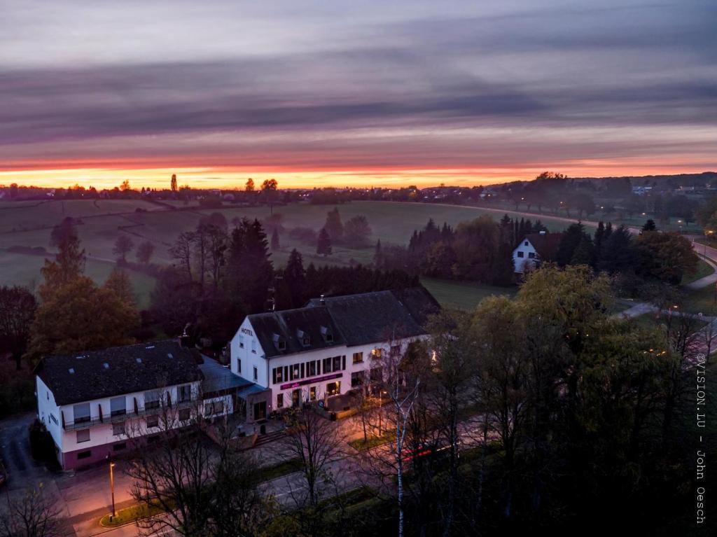 Hotel de la Station في Scheidgen: إطلالة على منزل عند غروب الشمس مع الضباب في المسافة