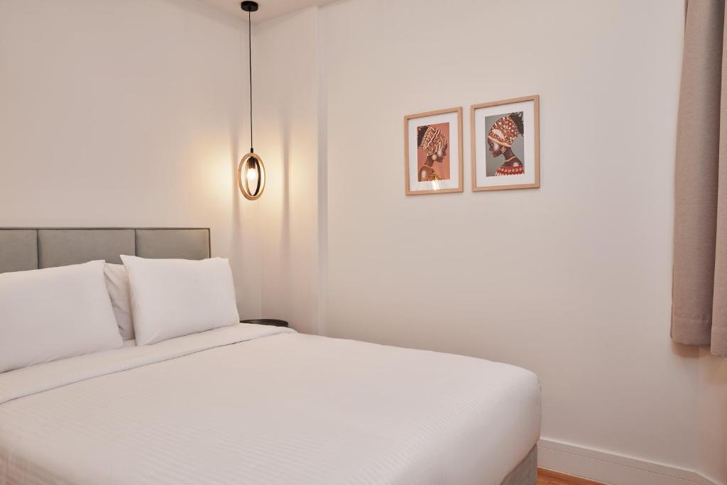 sypialnia z białym łóżkiem z dwoma obrazami na ścianie w obiekcie Urban Heights 3BD Apt, next to Hilton w Atenach