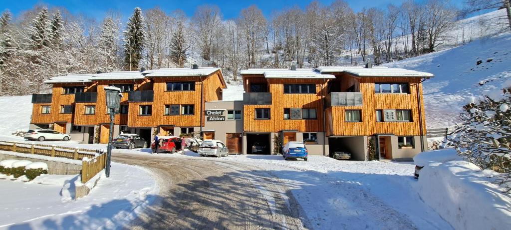 a building in the snow with cars parked in front at Chalet Ablon in Saalbach Hinterglemm