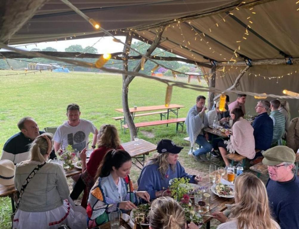 a group of people sitting at tables under a tent at Delightful Shepherd hut in Graffham