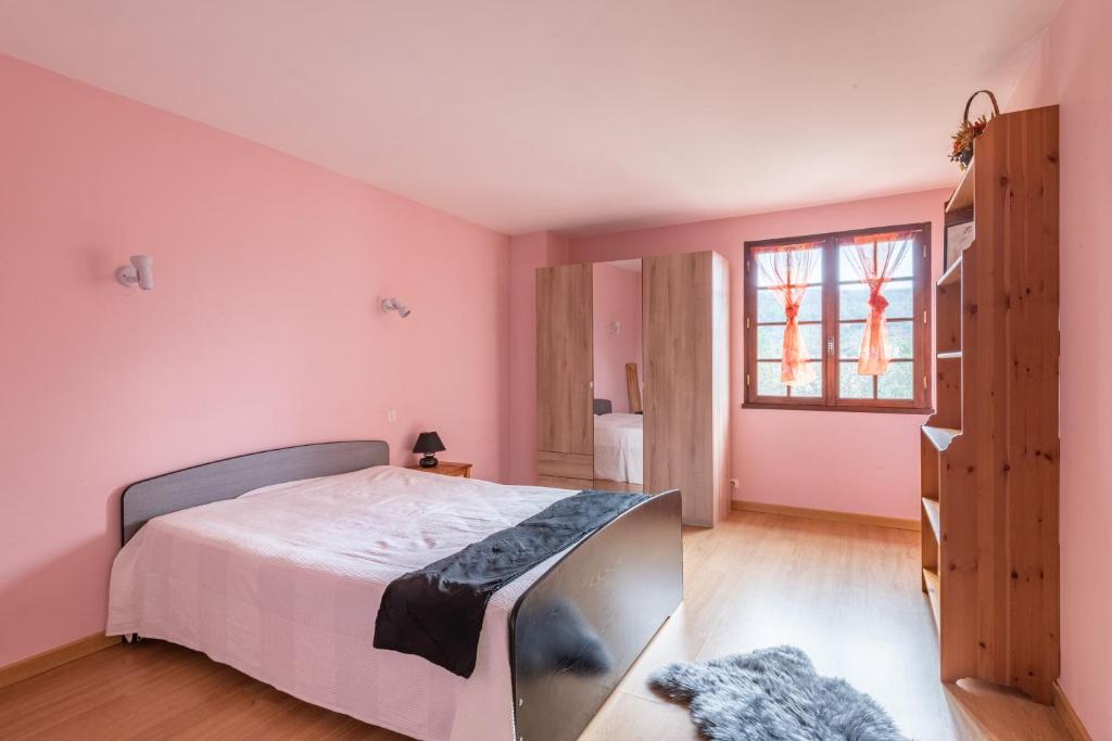 a bedroom with pink walls and a bed with a tv at L&#39;Espedes in Ruoms