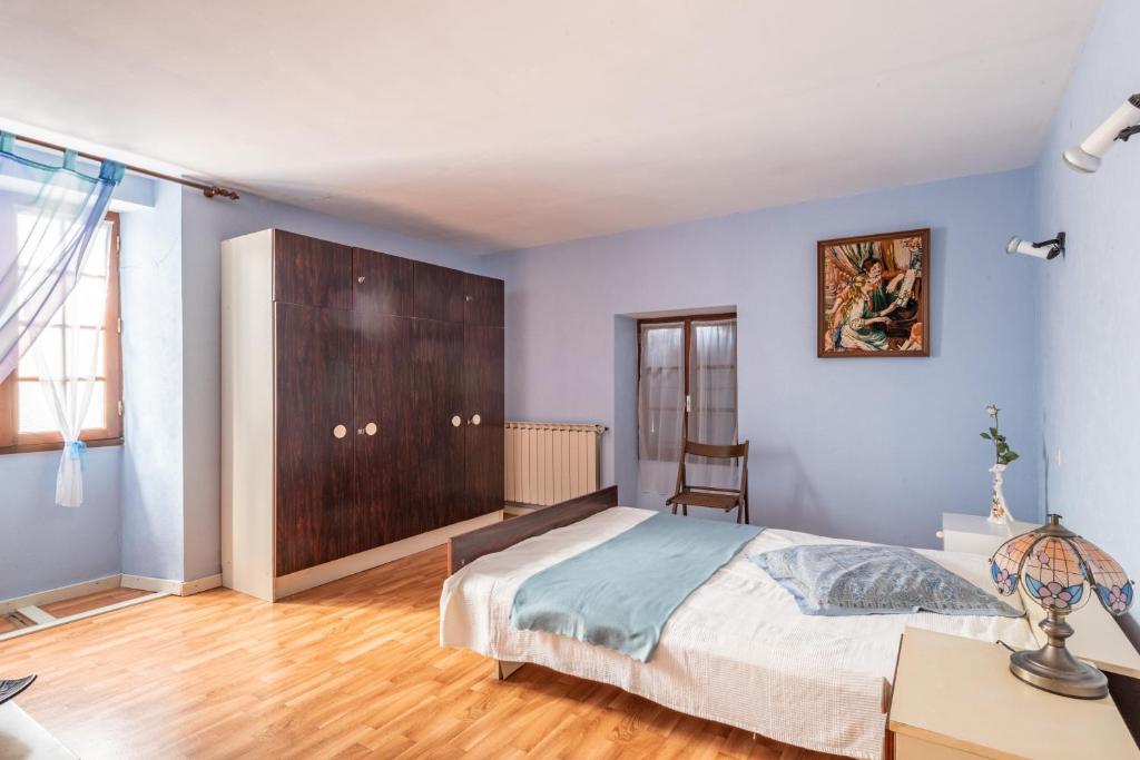 a bedroom with blue walls and a bed and a wooden floor at L&#39;Espedes in Ruoms