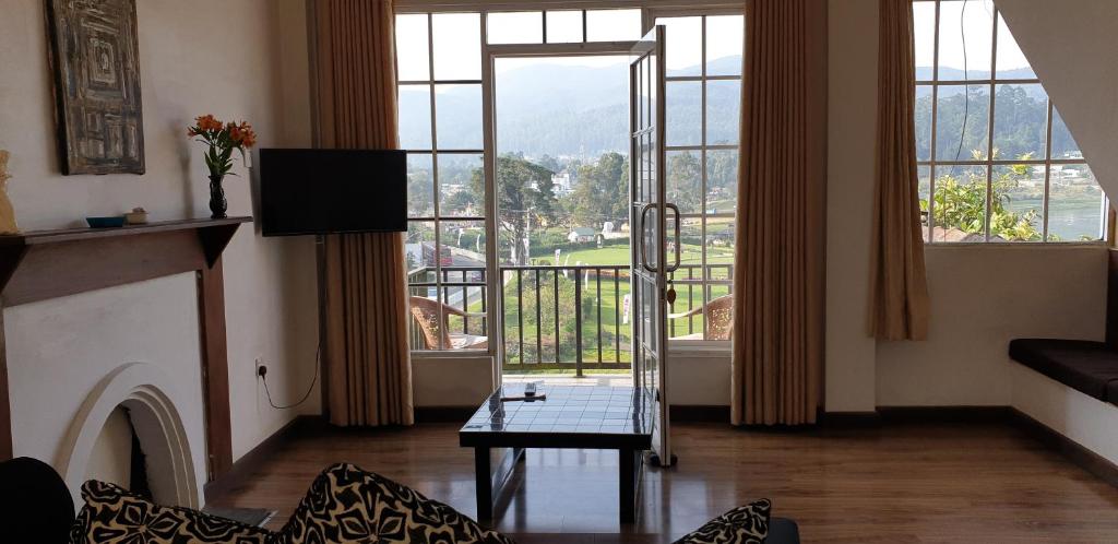 a living room with a fireplace and a large window at Medalin Lake Gregory in Nuwara Eliya