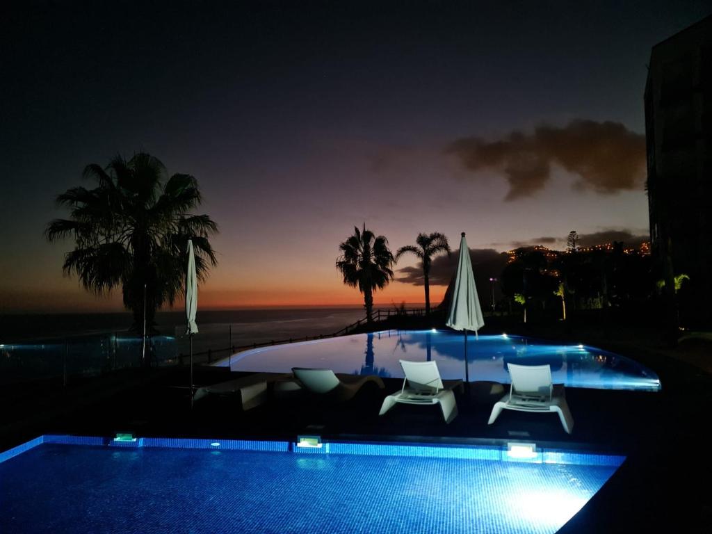 einen Pool mit 2 Stühlen und einem Sonnenschirm in der Unterkunft Peaceful Madeira Palace in Funchal