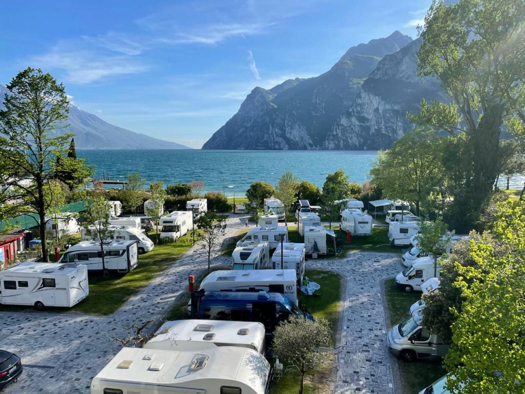 Kilka samochodów zaparkowanych obok jeziora w obiekcie Al Lago Camping & Rooms w mieście Riva del Garda