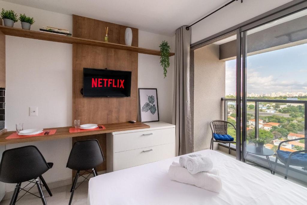 um quarto com uma cama, uma secretária e uma janela em Studio com lazer e varanda no Alto da Boa Vista em São Paulo