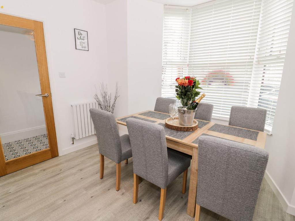 a dining room table and chairs with a vase of flowers at Cartref Clyd 55 in Porthmadog