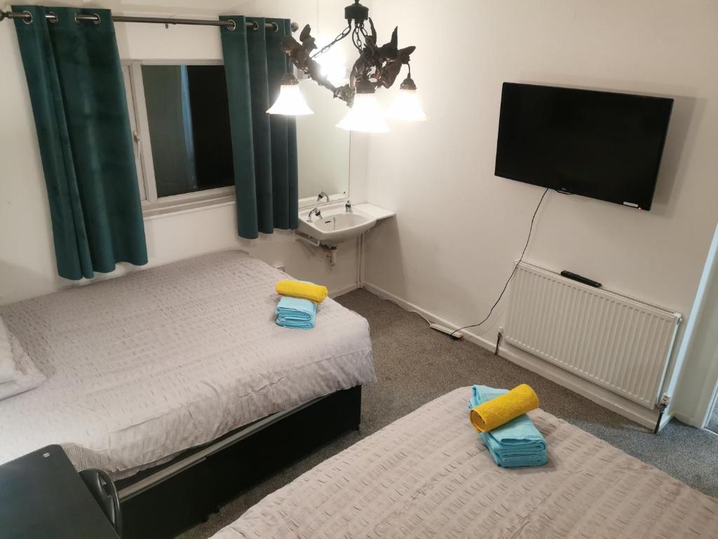 una camera con due letti, un lavandino e una TV di 116 Maison Dieu Road Room D in Dover a Kent