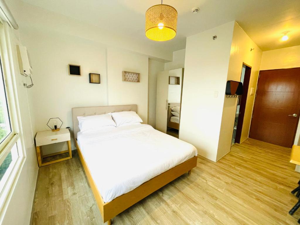 Un dormitorio con una gran cama blanca y una ventana en Cozy Condo bedroom in Bacolod City en Bacolod