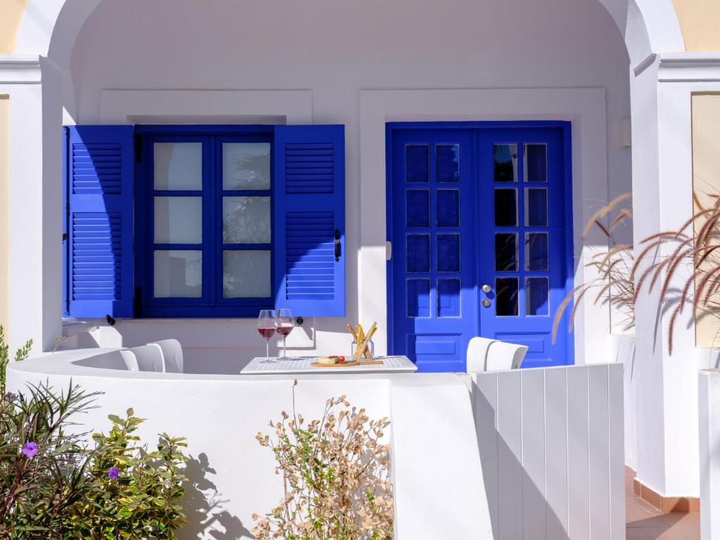費拉的住宿－Casa di Magi，一间设有蓝色门和一张带葡萄酒玻璃的桌子的房子