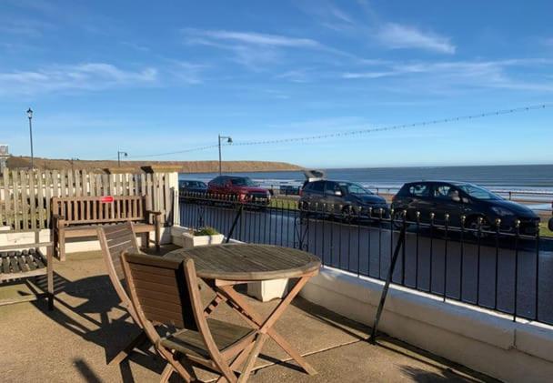 Una mesa y sillas en un balcón con vista al mar. en Beach Apartment - Seafront Apartment, en Filey