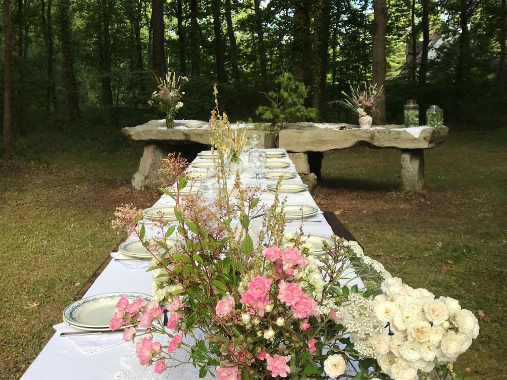 een lange tafel met borden en bloemen erop bij Au Pain des Anges in Saint-Gervais en-Belin