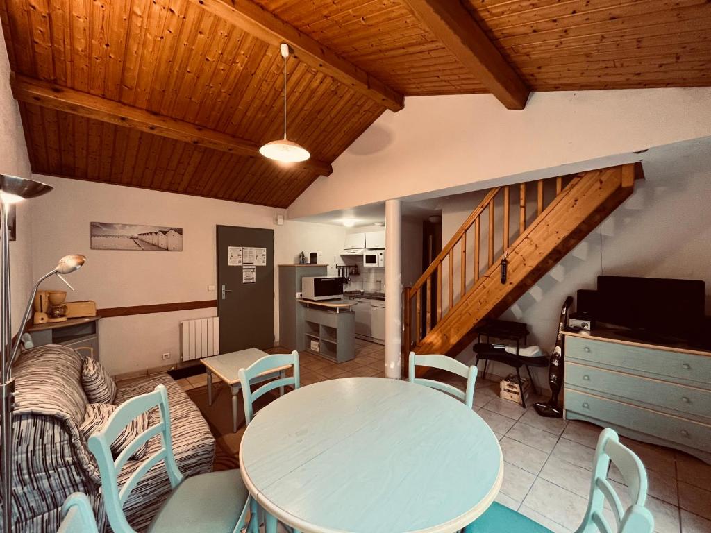 salon ze stołem, krzesłami i schodami w obiekcie Le Victoria, piscine et forêt w mieście Saint-Jean-de-Monts