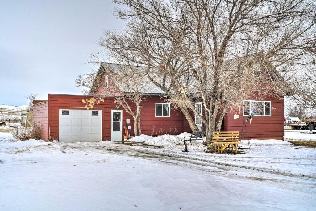 a red house with a garage in the snow at Charming Corral Creek Ranch House in Circle in Circle