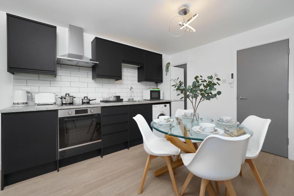 uma cozinha com uma mesa de vidro e cadeiras brancas em Stunning Duplex near Canary Wharf & O2 & City Views em Londres