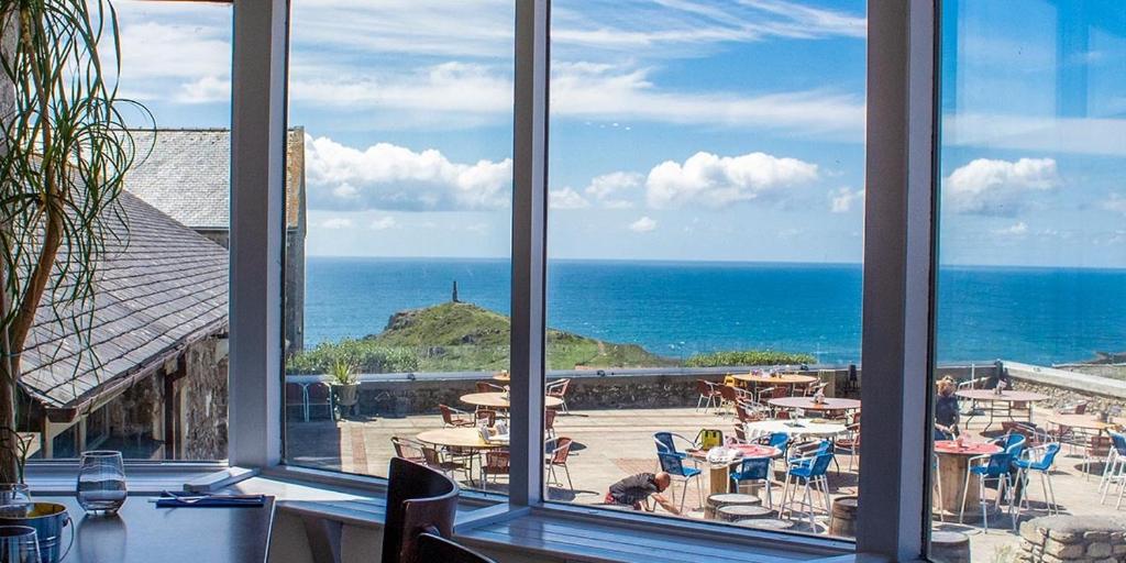 einen Blick auf das Meer von einem Restaurantfenster aus in der Unterkunft Cape Cornwall Club in St Just