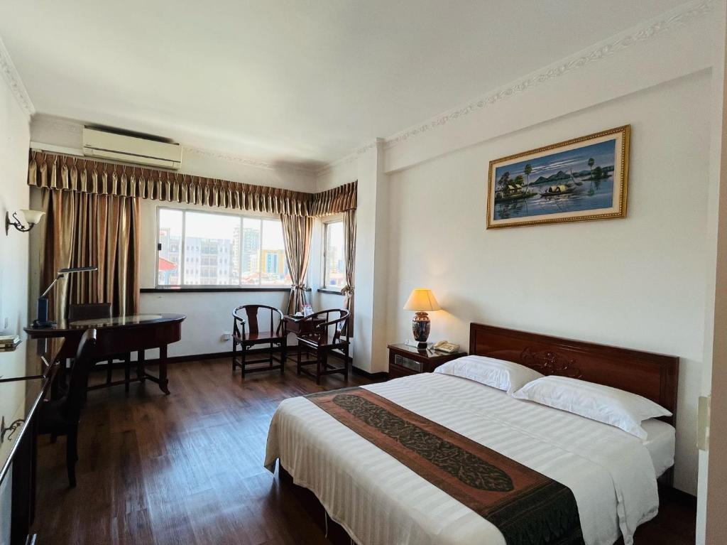 a hotel room with a large bed and a desk at Chung Hsin Hotel 中信酒店 in Phnom Penh