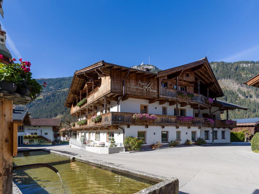 a large building with balconies and a body of water at Apart Landhaus Heim in Mayrhofen