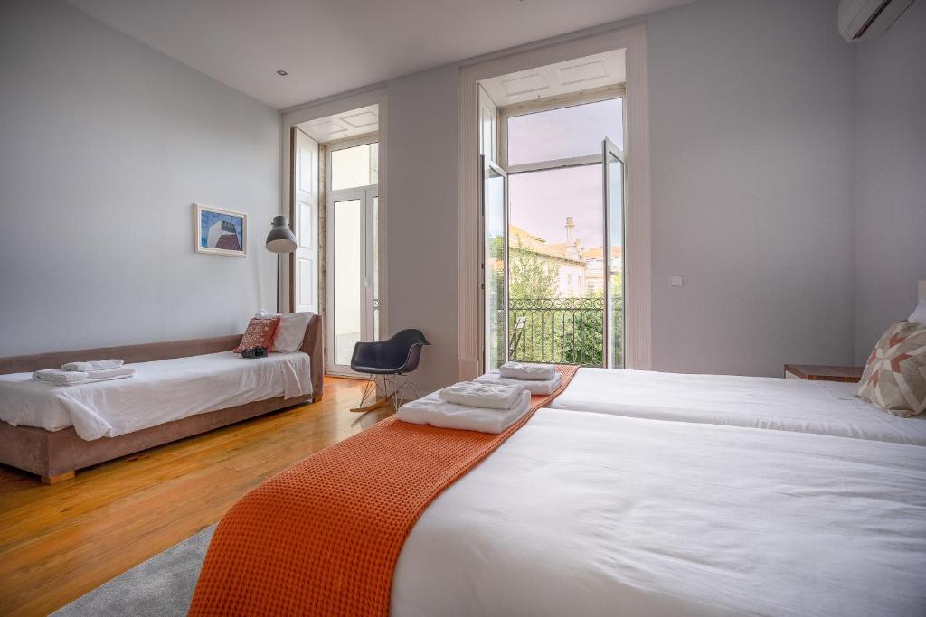 a bedroom with two beds and a couch and windows at Oporto Trendy Apartments in Porto