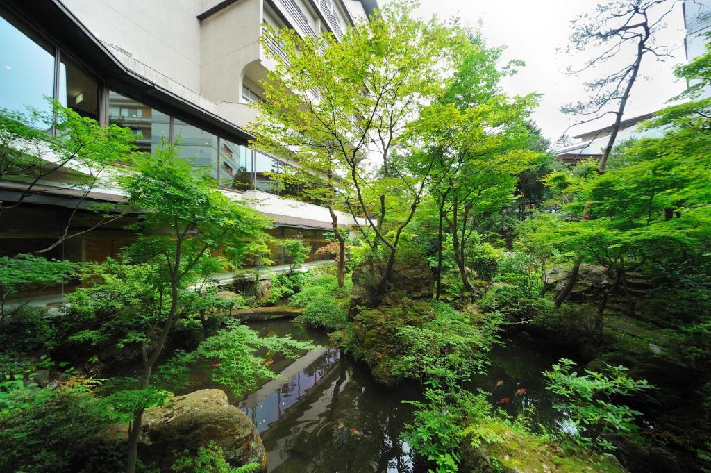 een tuin voor een gebouw met een rivier bij Senkeien Tsukioka Hotel in Kaminoyama