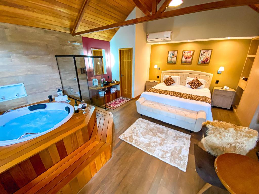 ein großes Schlafzimmer mit einer Badewanne und einem Bett in der Unterkunft Chalés Princesa Isabel in Petrópolis