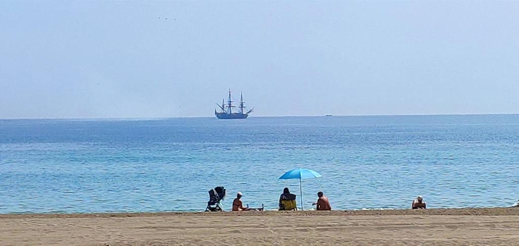 un groupe de personnes assises sous un parasol sur une plage dans l'établissement On the beach! Frente al Paseo Marítimo, Parking y Piscina, à Malaga