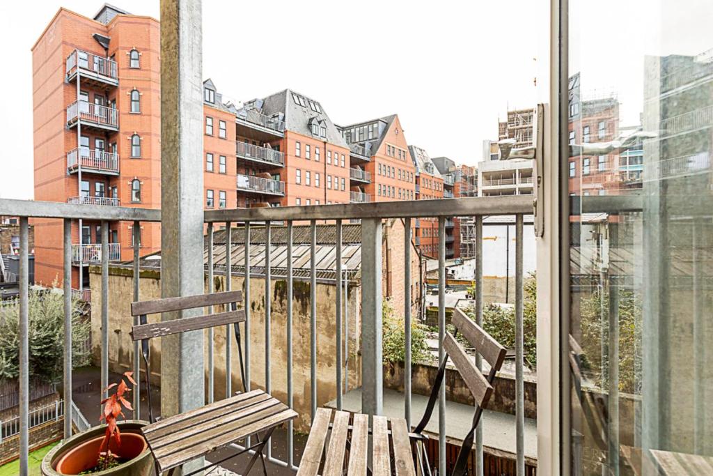 uma varanda com um banco e vista para a cidade em Cosy Apartment In Vibrant Whitechapel em Londres