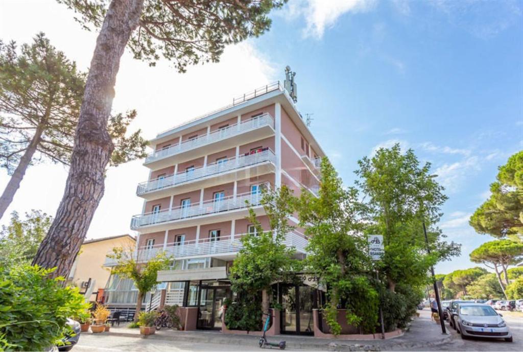 un grand bâtiment rose avec des arbres devant lui dans l'établissement Hotel La Torre, à Cervia