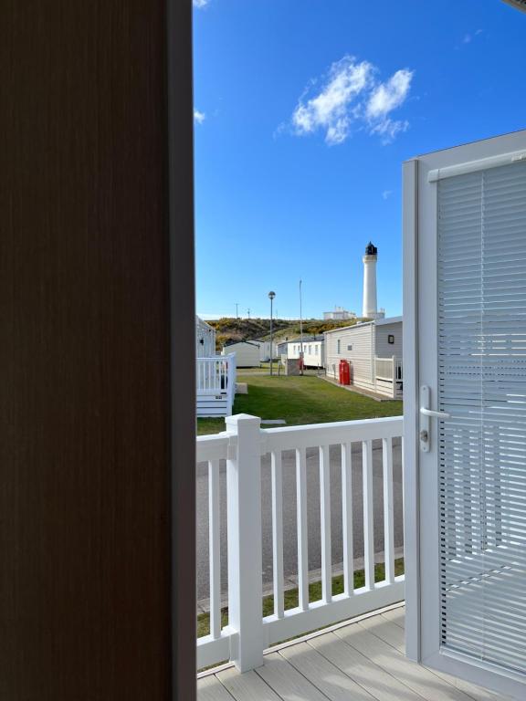a door leading to a balcony with a lighthouse at Playa la Casa in Lossiemouth