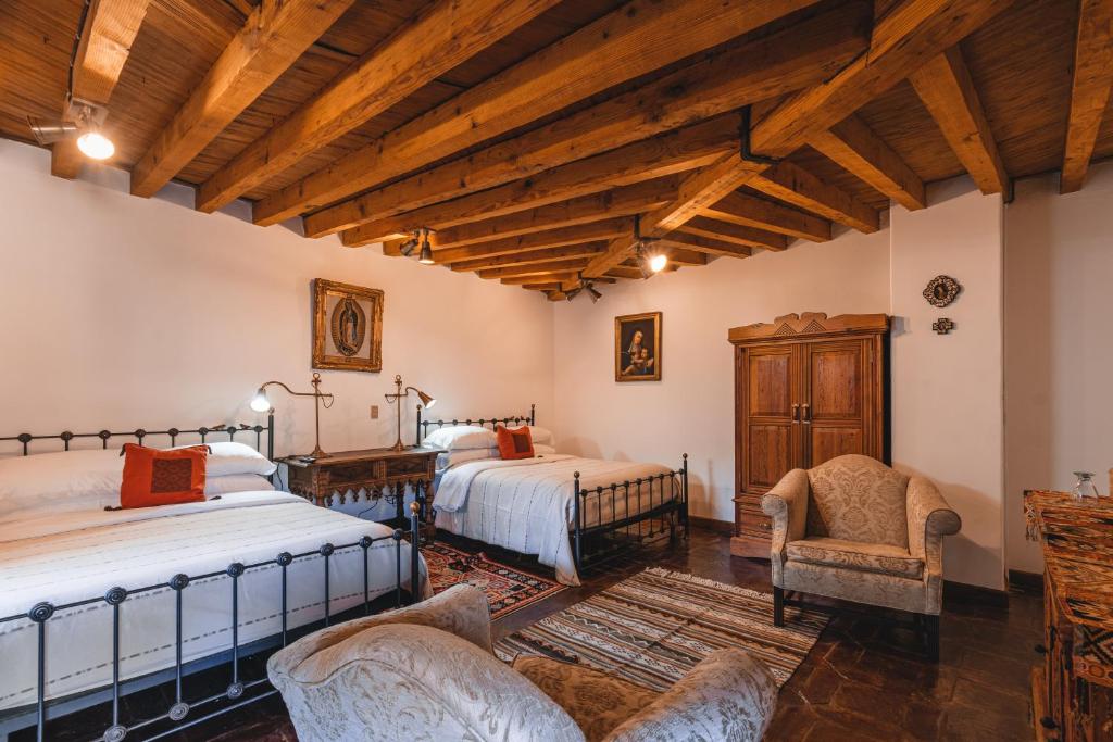 a bedroom with two beds and a desk and chairs at El Edén Hotel Boutique in Pátzcuaro