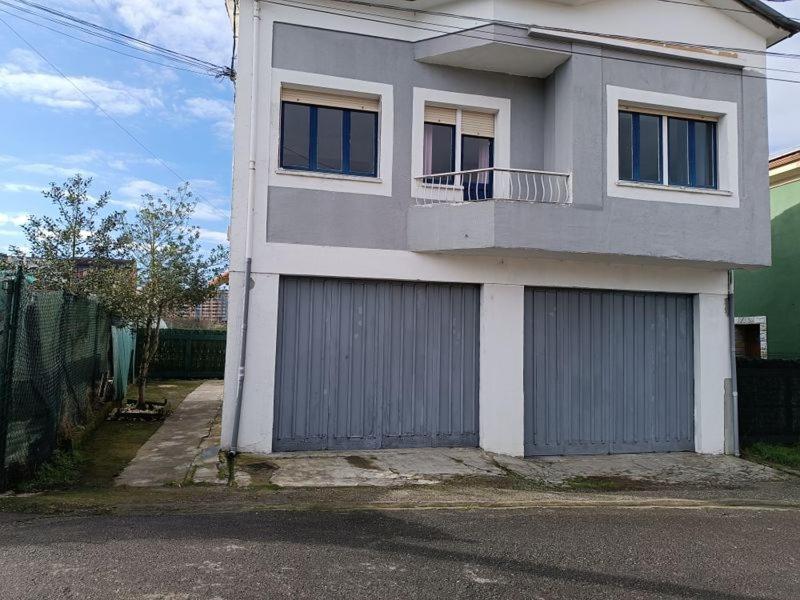 ein weißes Haus mit zwei Garagentüren und einem Balkon in der Unterkunft Casa Oviedo centro in Oviedo