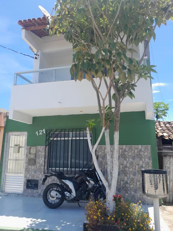 una motocicleta estacionada junto a un árbol frente a un edificio en Suíte 1 Zona Sul Ilhéus próximo a praia, en Ilhéus