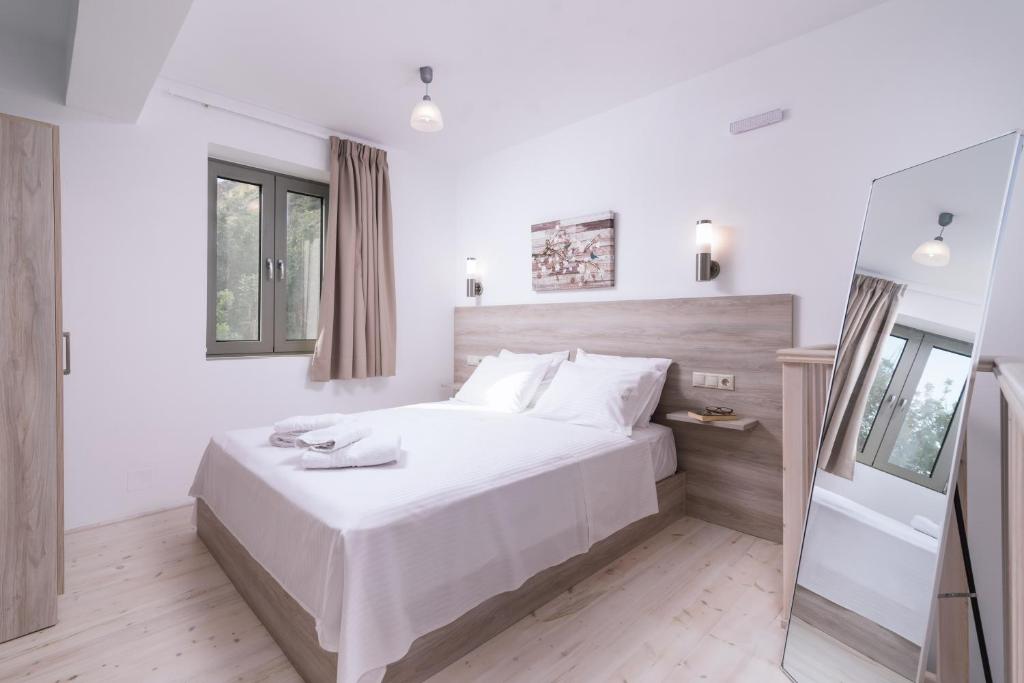 a white bedroom with a large bed and a mirror at Matala Prime Villas in Matala