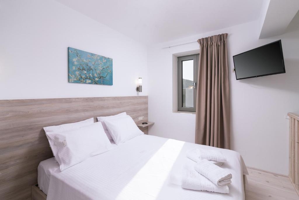 a bedroom with a white bed with a television on the wall at Matala Prime Villas in Matala