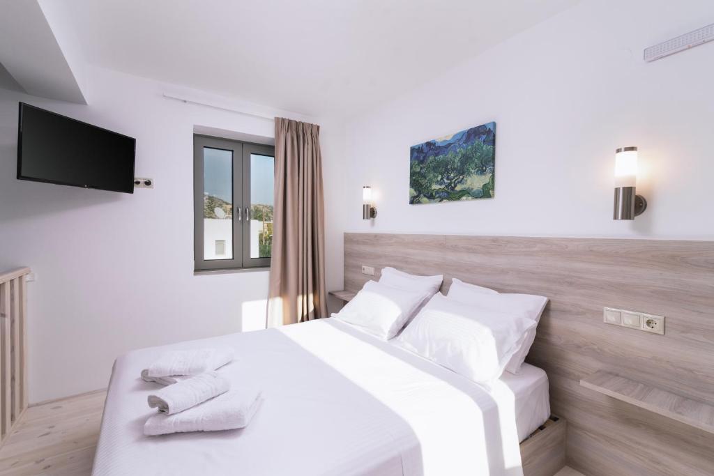 a white bedroom with a white bed and a tv at Matala Prime Villas in Matala