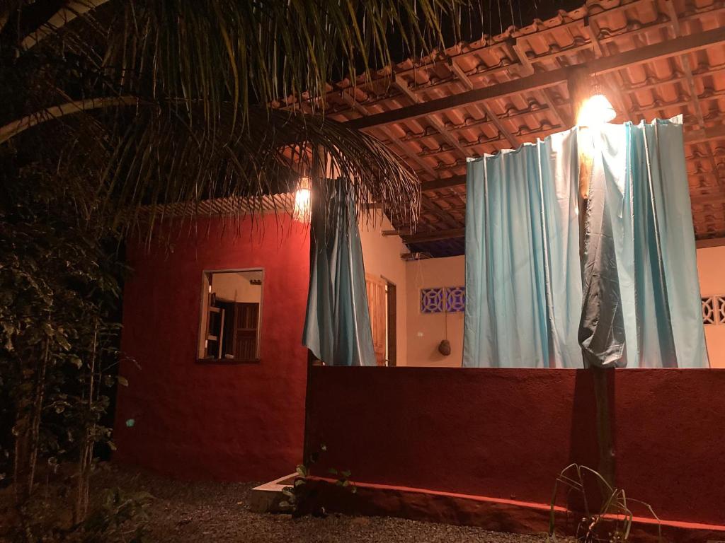 Habitación con cortinas azules y pared roja. en Casa Vila Camboinha, en Itacaré