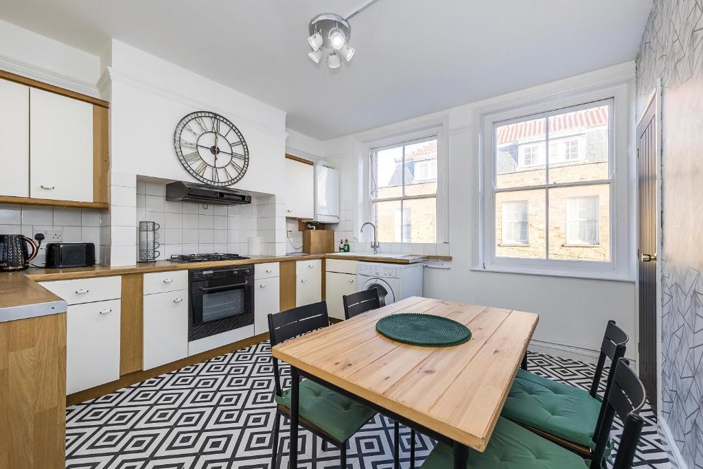 a kitchen with a wooden table and some chairs at Indigo City Apartment in London