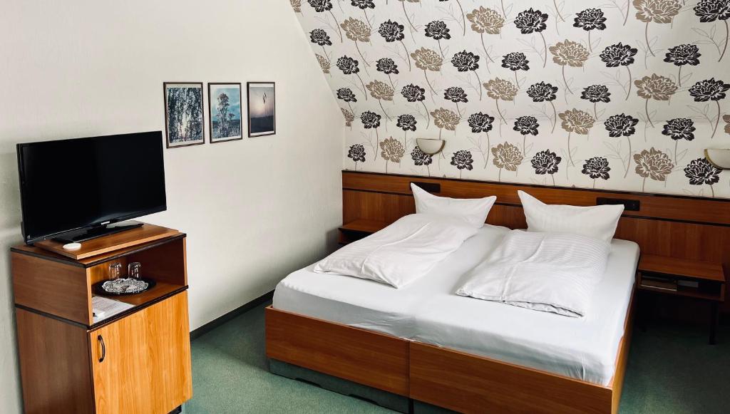 a bedroom with a bed and a flat screen tv at Landhotel Laarmann in Lennestadt