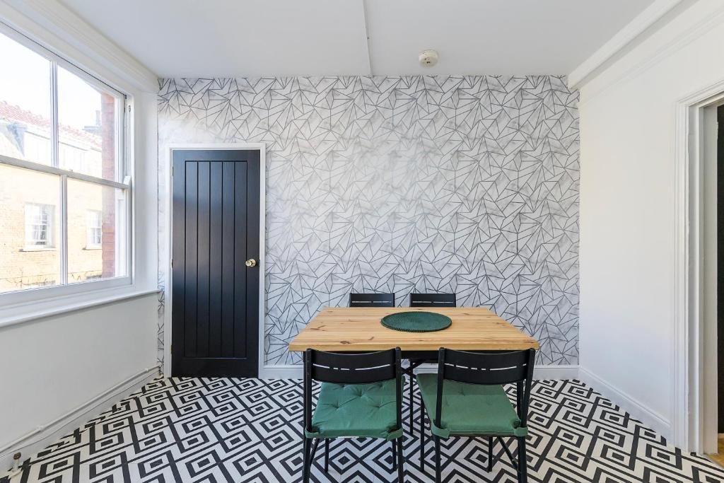 a table and chairs in a room with a wall at Indigo City Apartment in London