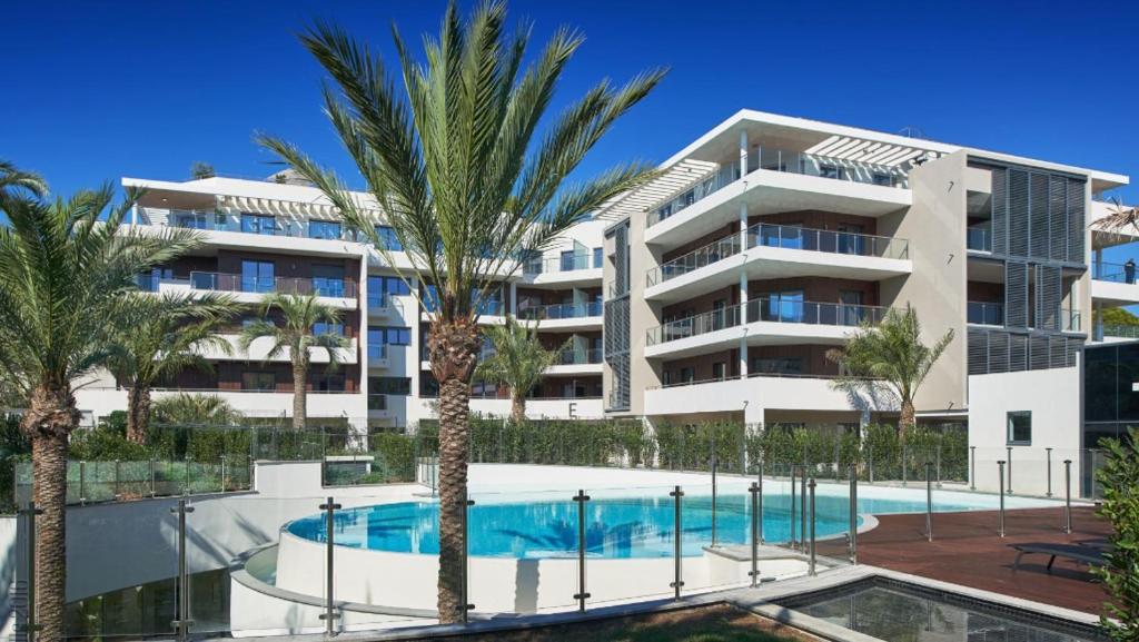 um edifício de apartamentos com piscina e palmeiras em Parc du Cap Luxury Apartment em Antibes