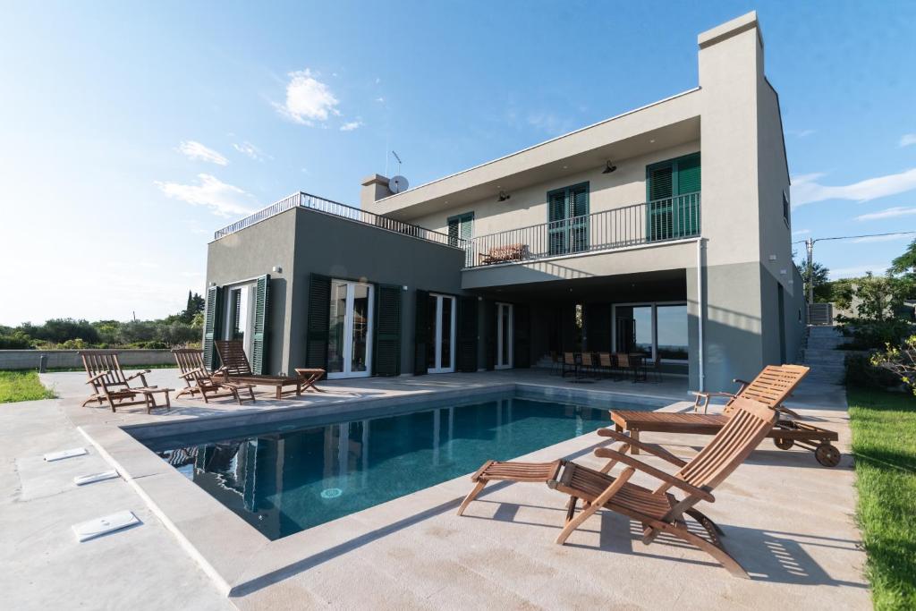 ein Haus mit einem Pool und einigen Stühlen in der Unterkunft Villa Gorana in Zadar