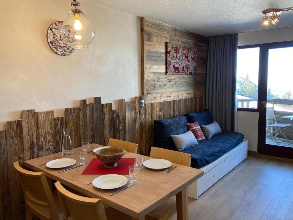 ein Esszimmer mit einem Tisch und einem blauen Sofa in der Unterkunft Appartement Avoriaz, 2 pièces, 4 personnes - FR-1-634-76 in Morzine