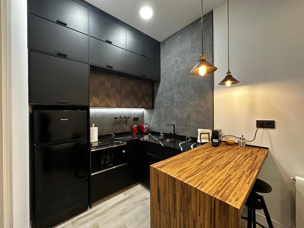 cocina con nevera negra y encimera de madera en CC Atocha Apartments, en Madrid