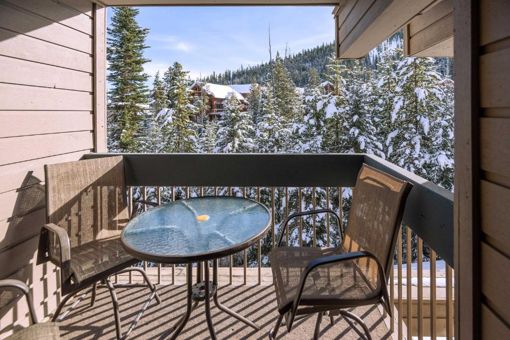 a table and chairs on a balcony with snow covered trees at Steps to Ski Lifts - Condo with Walk-Out Patio! in Big Sky