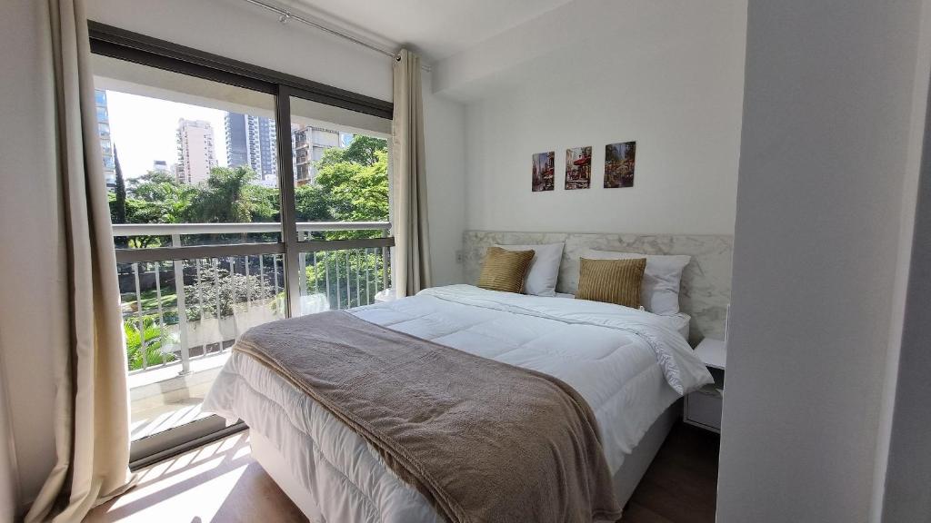 a bedroom with a bed and a large window at Canal do Anfitrião | Studios Jauperi in Sao Paulo